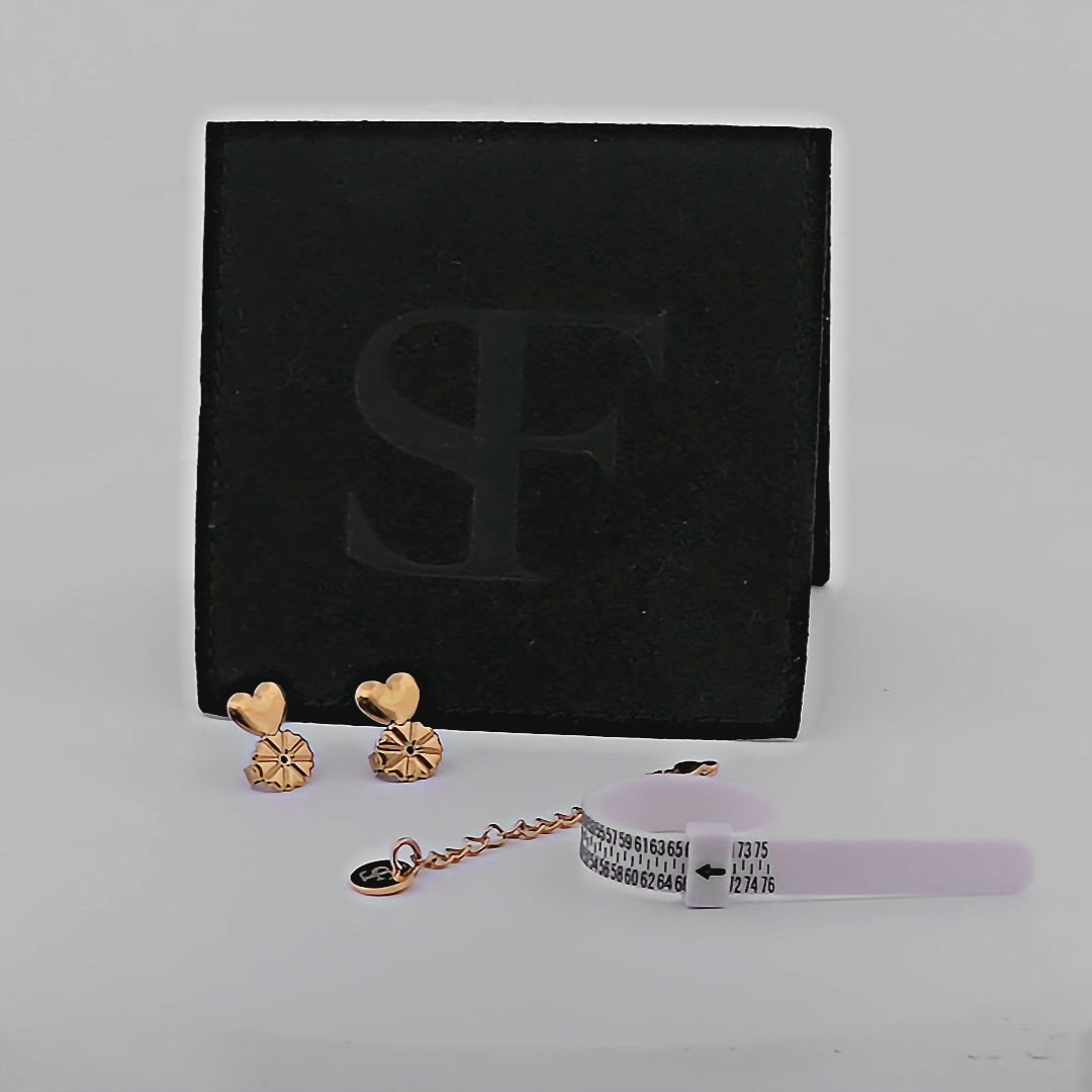 Svart smyckespåse från Susanna Falken Jewellery fylld med måttband för fingrar, förlängningskedja och Stadig Snurrebuss i valbar färg – silver eller guld – på vit bakgrund.