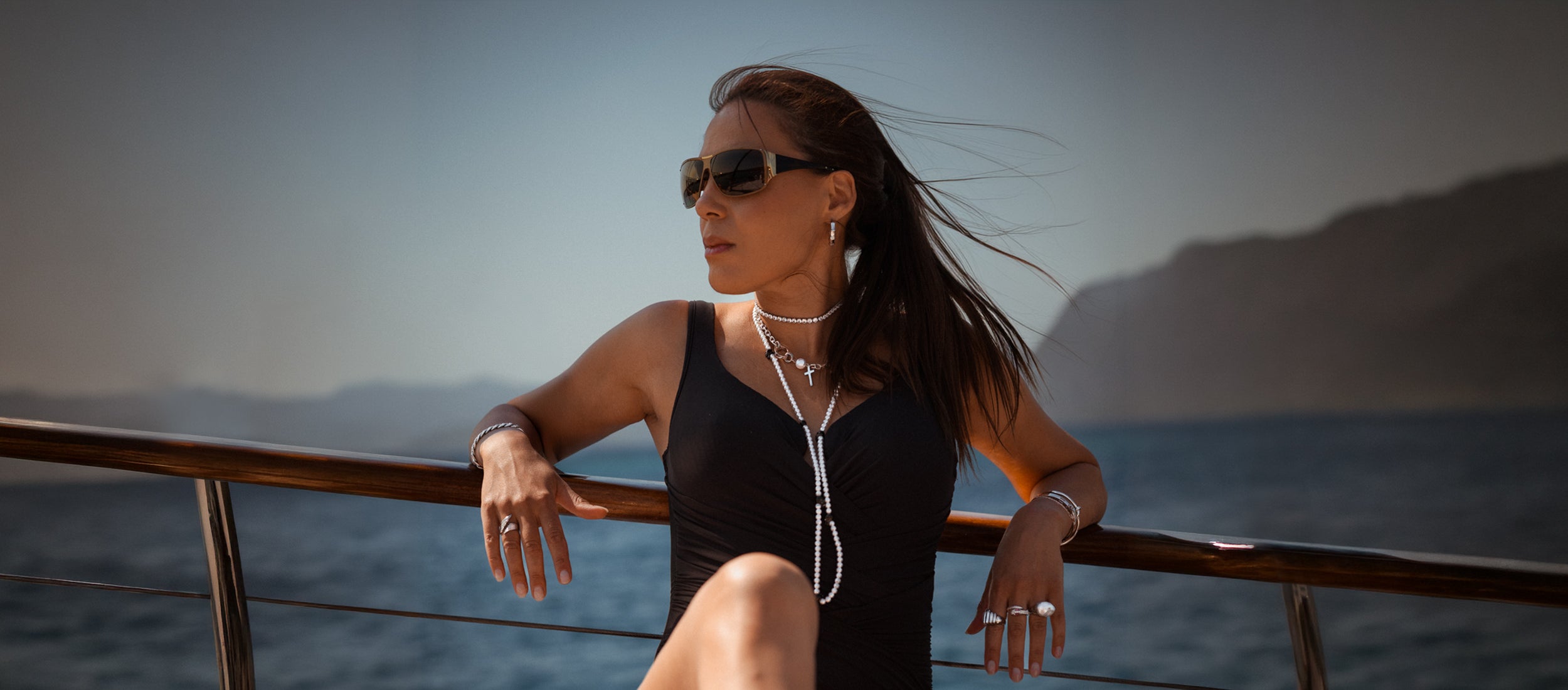 Silverfärgade halsband, armband och ringar på kvinna i sommarmiljö – Susanna Falken Jewellery